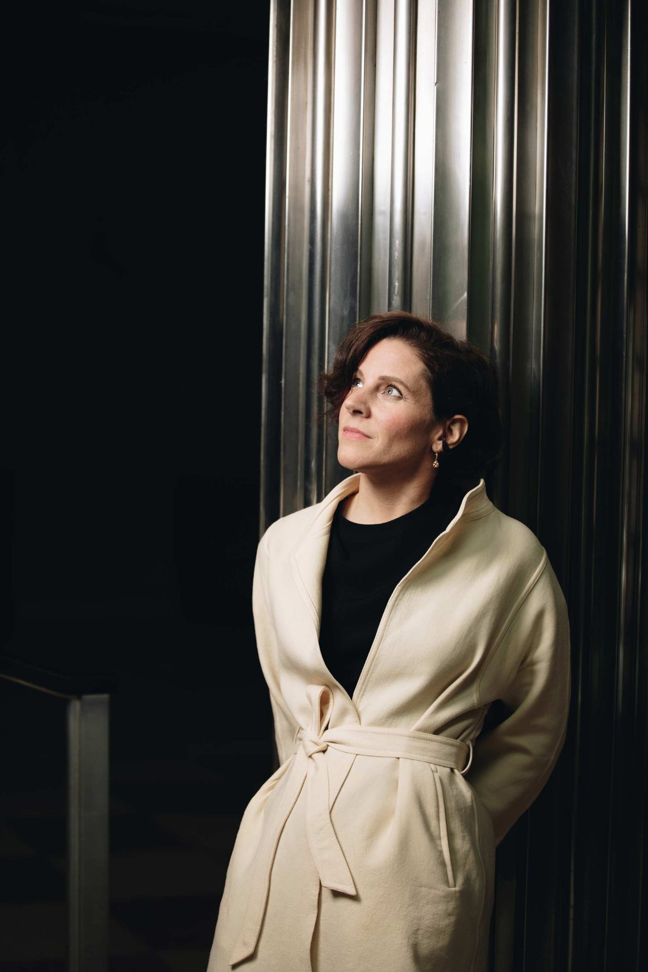 Editorial portrait of Teresa Zimmermann in a cream coat against fluted silver columns